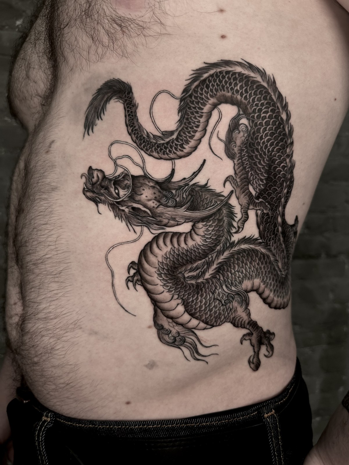 Detailed black and grey dragon tattoo